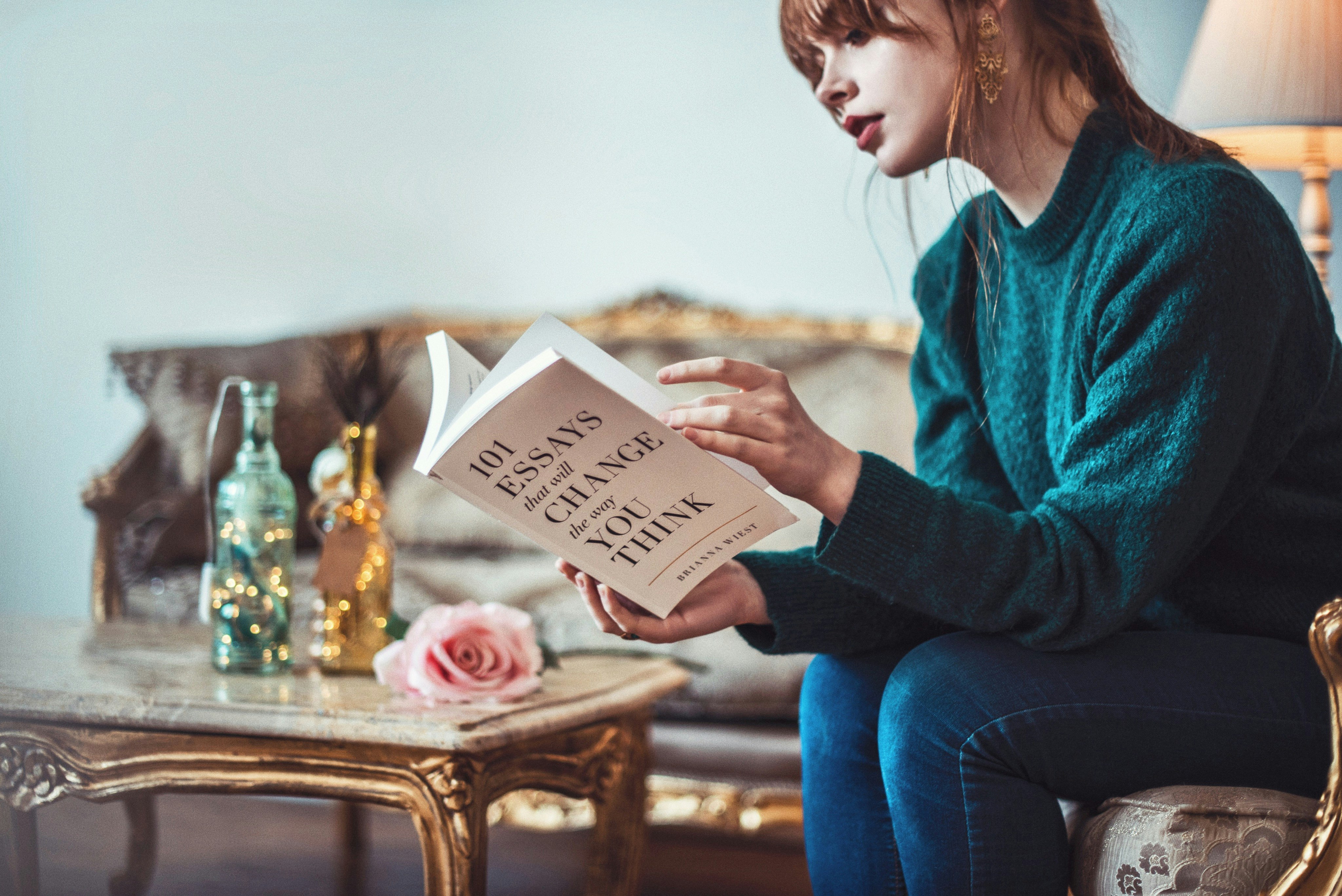 woman sitting down near table reading 101 Essays book